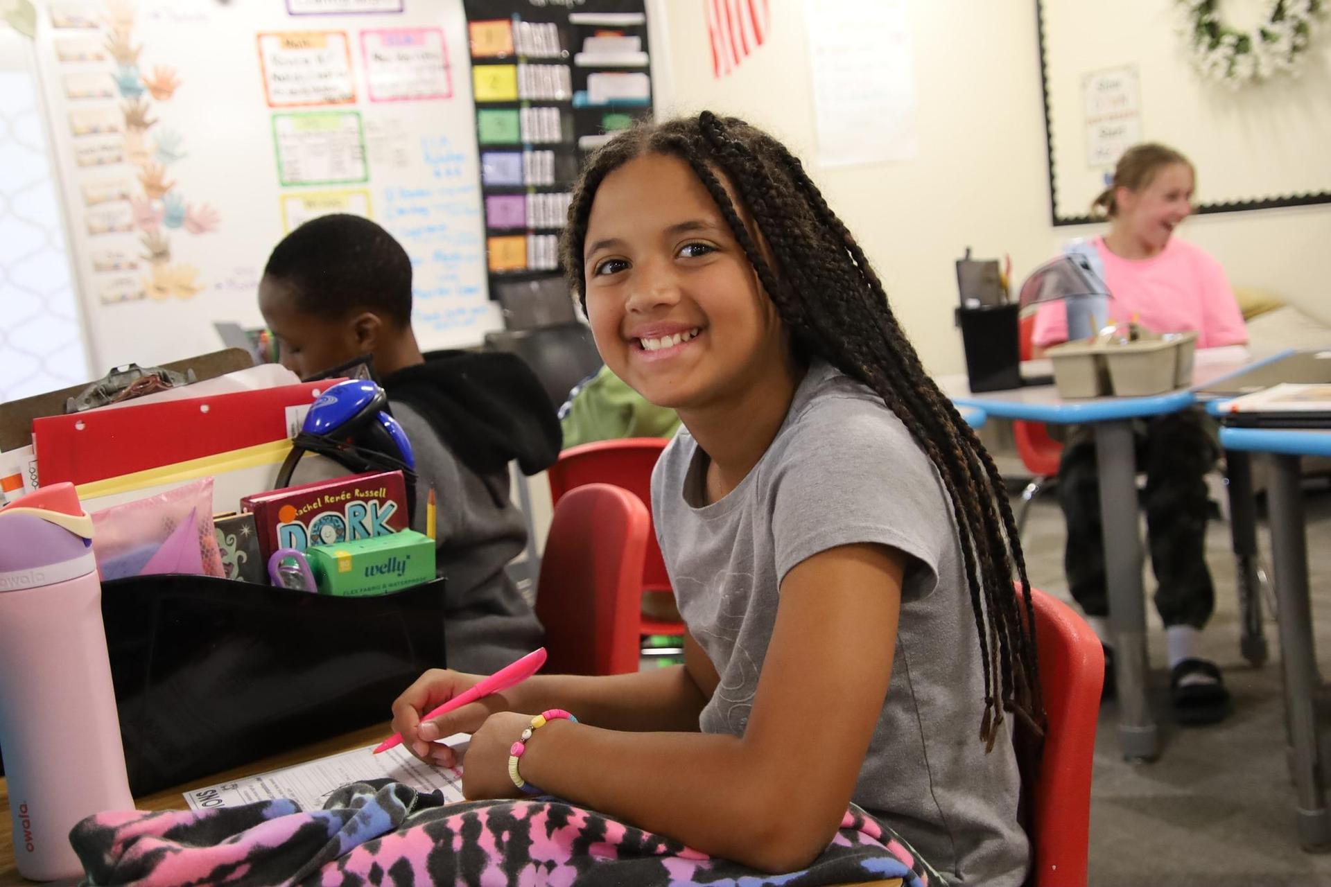 elementary school girl smiling at the camera in a classroom