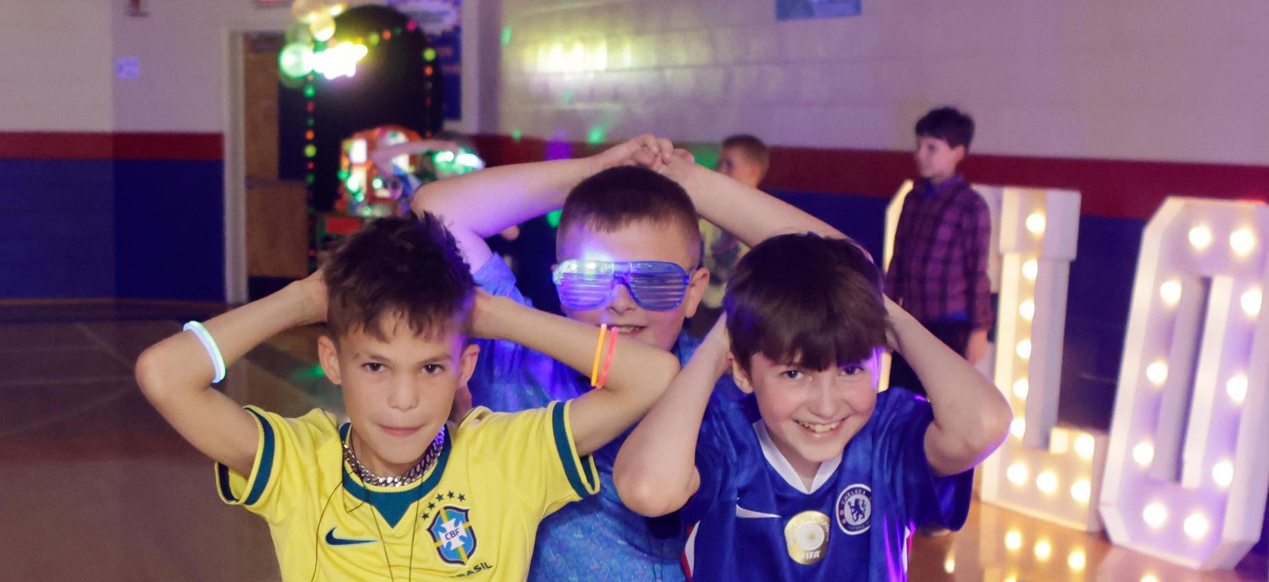 Three boys in colorful jerseys enjoying a fun event with neon lights.