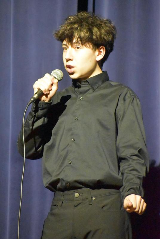 Young man singing into a microphone during a performance.