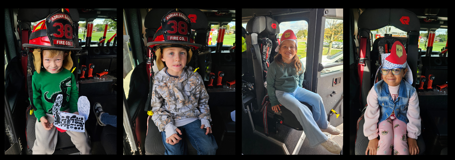 Four children seated in a fire truck, wearing fire hats and smiling.