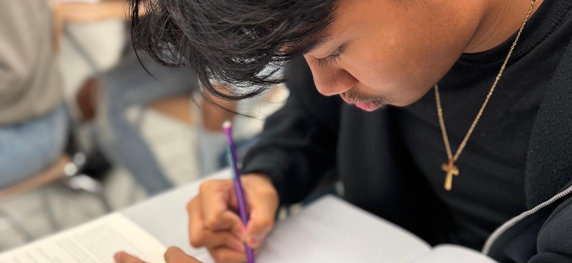 Student reading and writing at a desk
