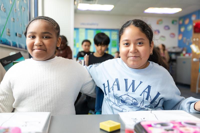 Two female elementary students smiling in class