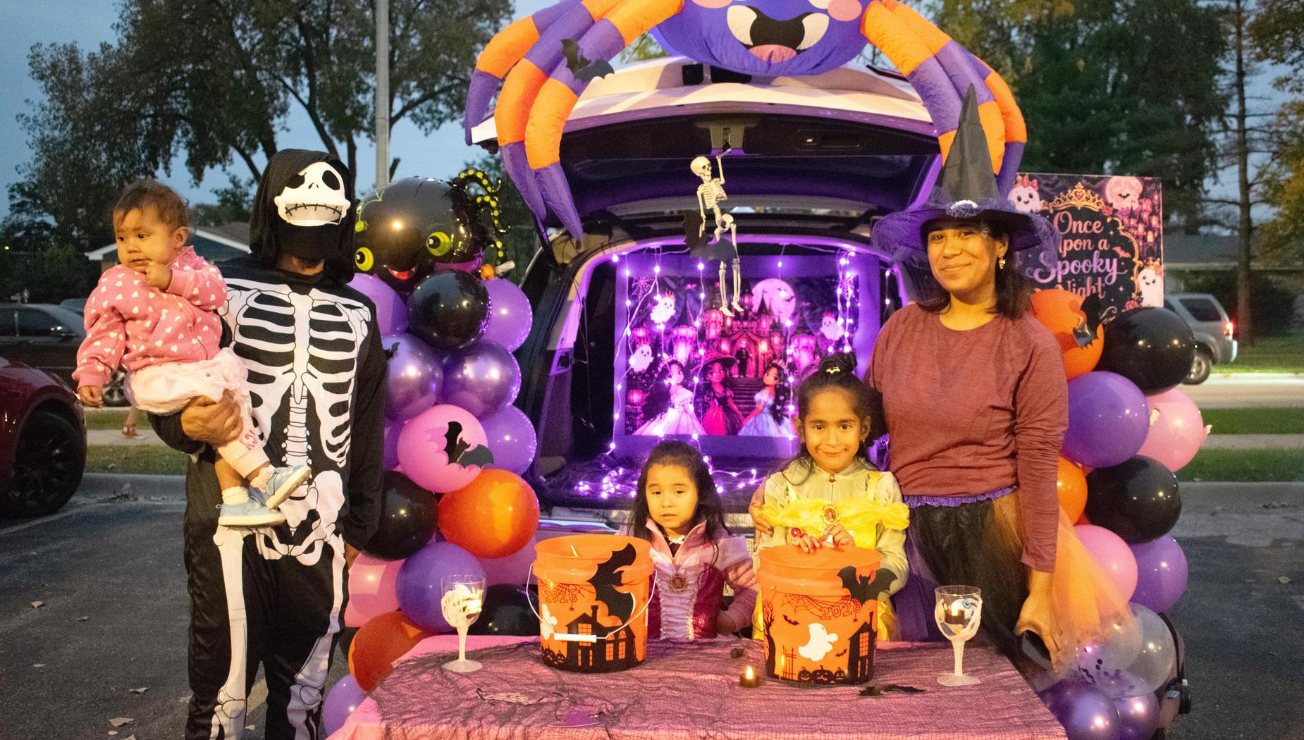 A festive Halloween trunk setup with a skeleton and children in costumes.