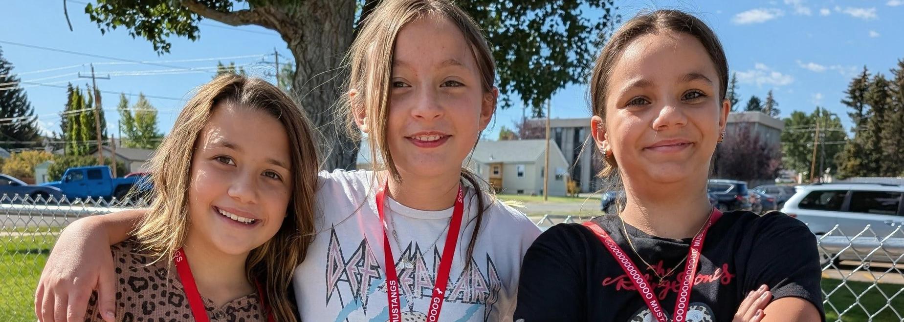 Three girls posing with lanyards, wearing leopard print and casual outfits.