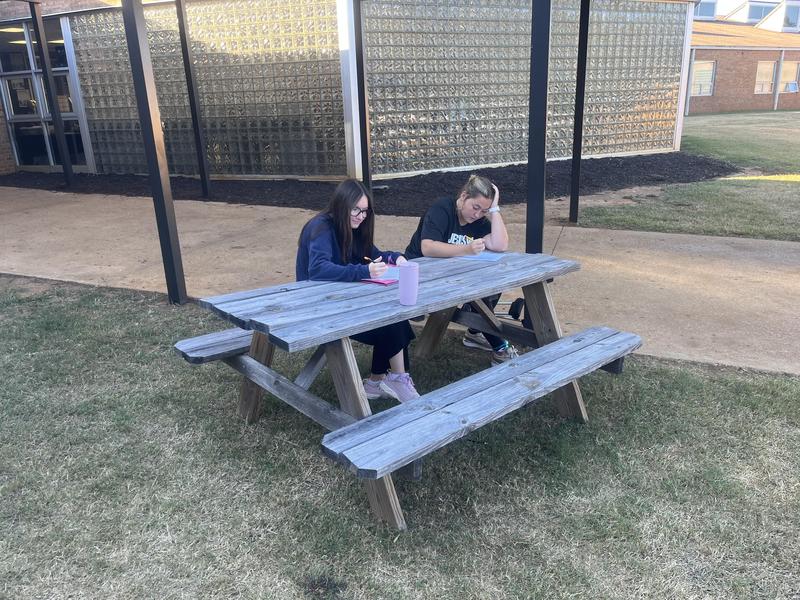 RG and LK sitting at picnic table writing