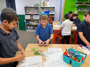 A third grade boy experimenting with unbalanced force using carboard and rubber bands.