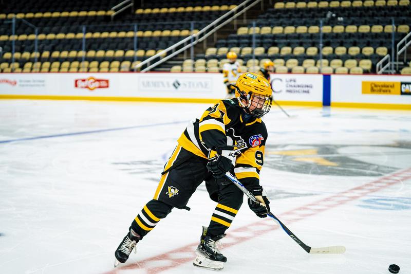 boy hockey player on ice dressed in penguin gear with stick