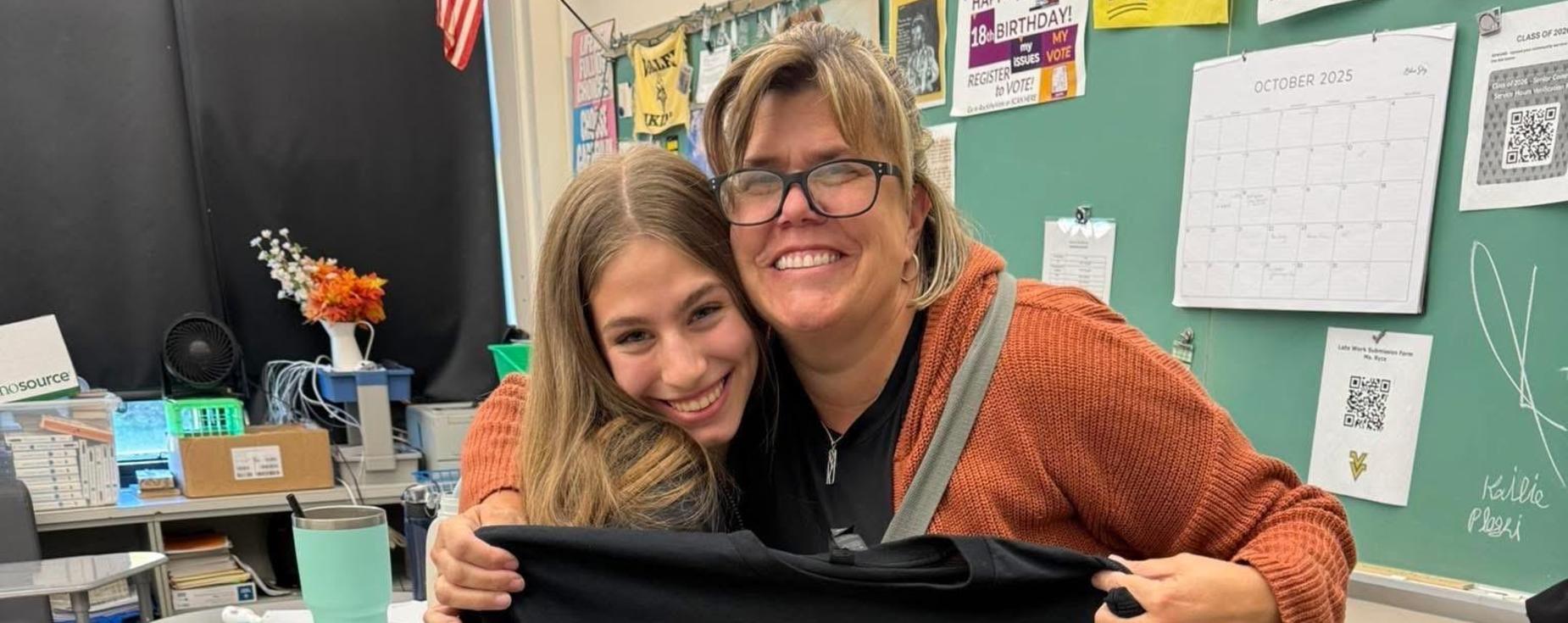Student giving a teacher a shirt