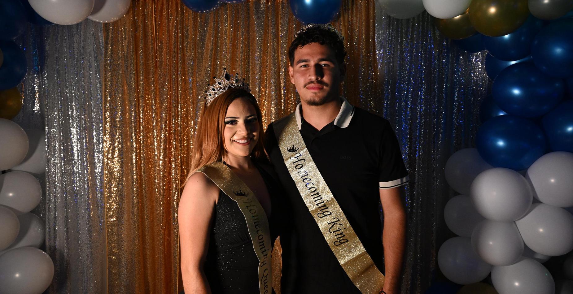 The Homecoming king and queen smile together beneath the balloon arch. Select to view Homecoming photos.