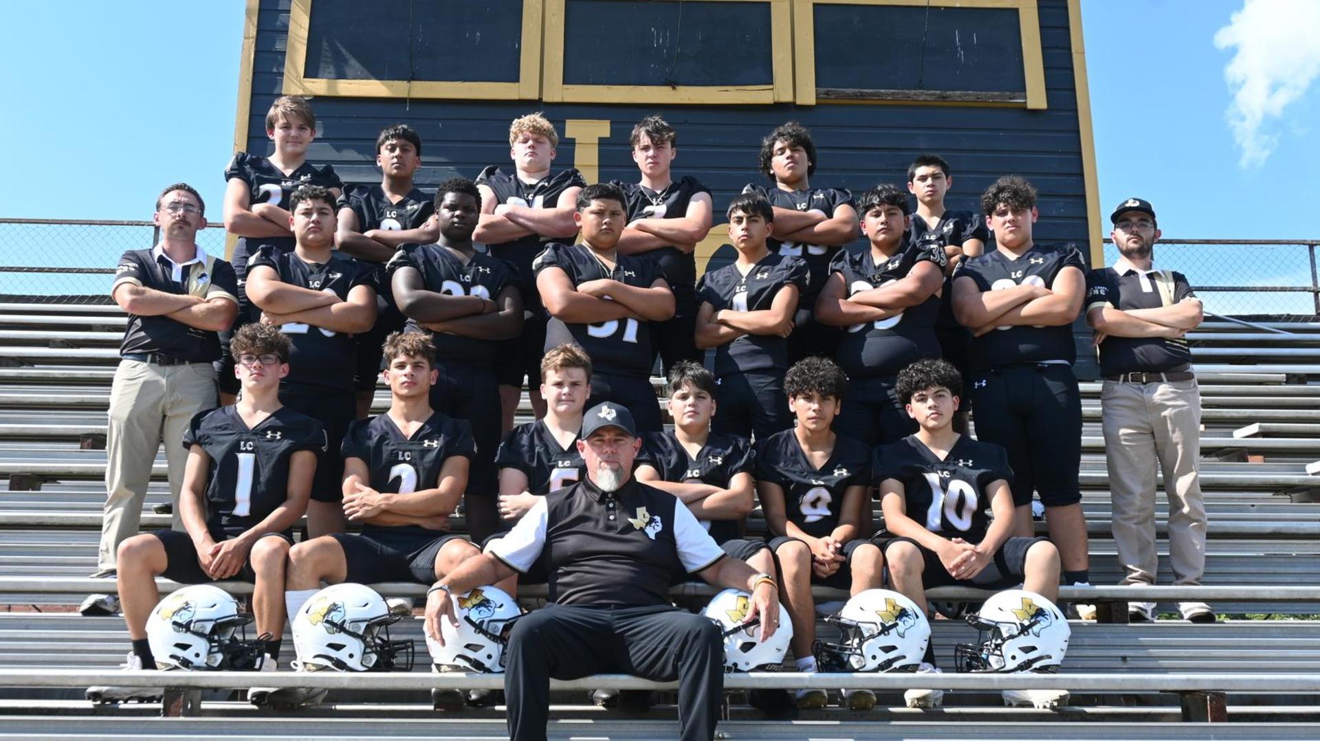 A high school football team posing together on bleachers with coaches.