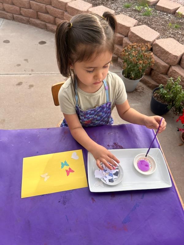 Title: Gluing Description: Anastasia is exercising her fine motor skills and creativity utilizing a thin brush and glue (Art).