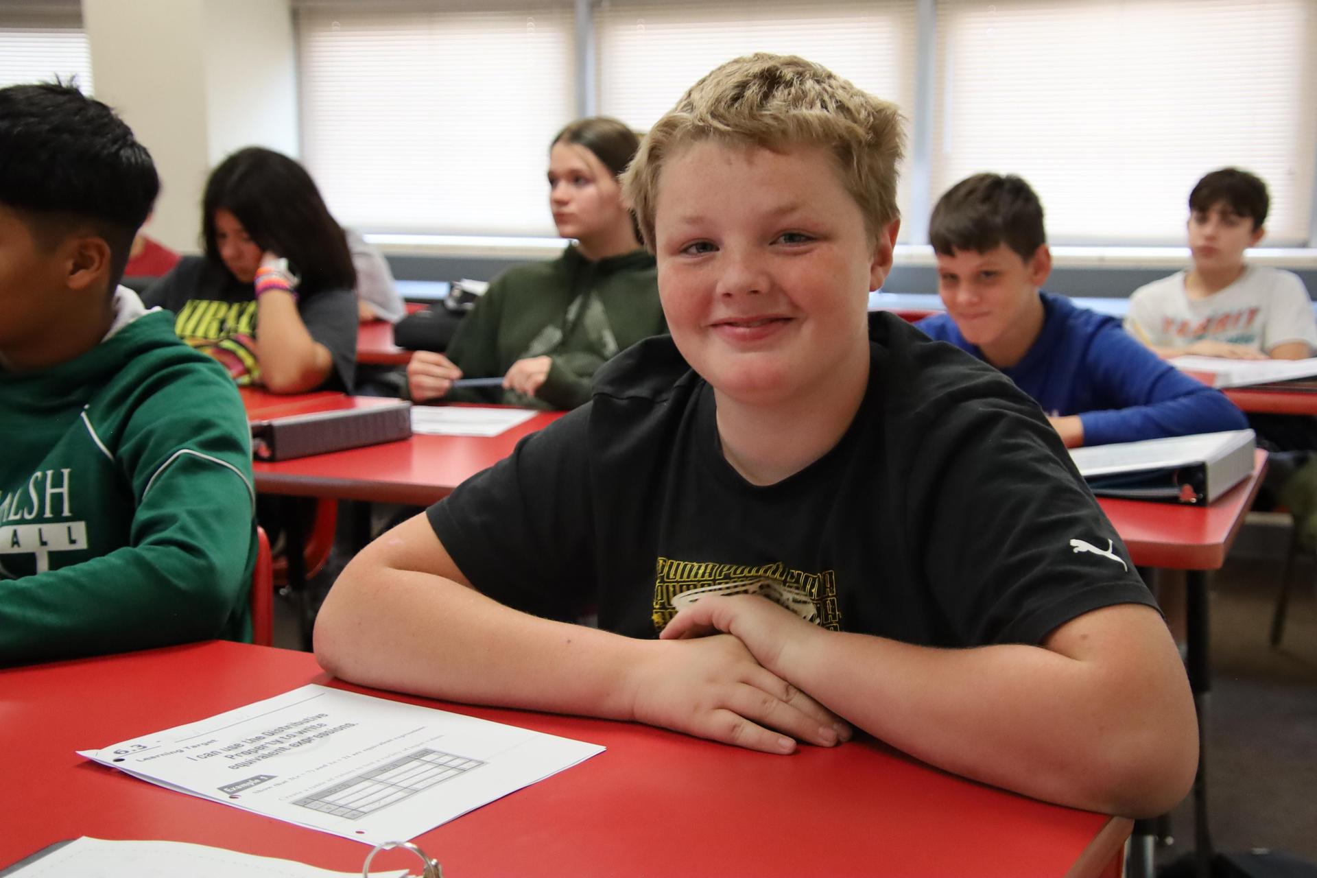 middle school boy smiling at camera in the classroom