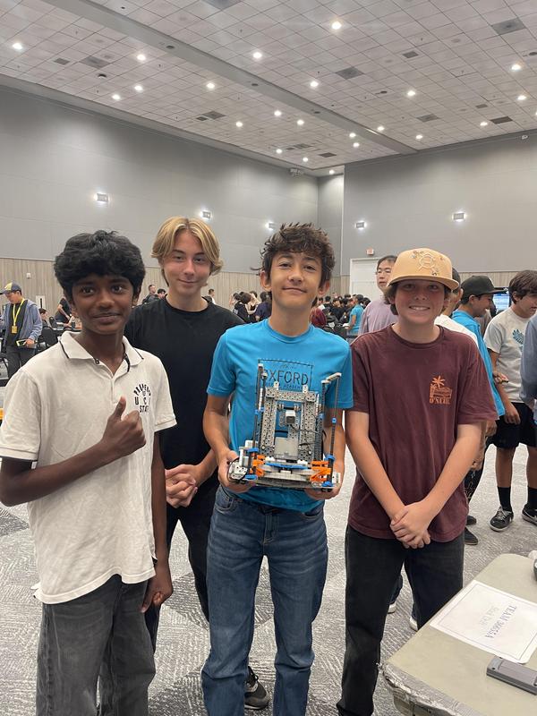 4 kids holding their robot at the competition