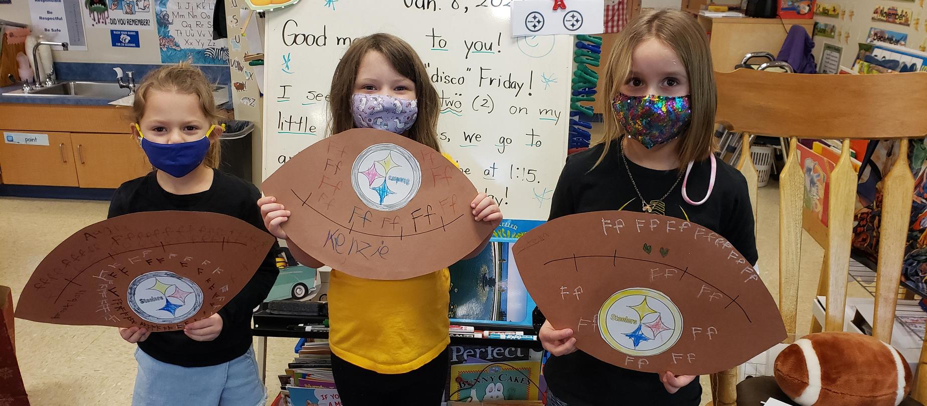 kindergarten students posing with footballs
