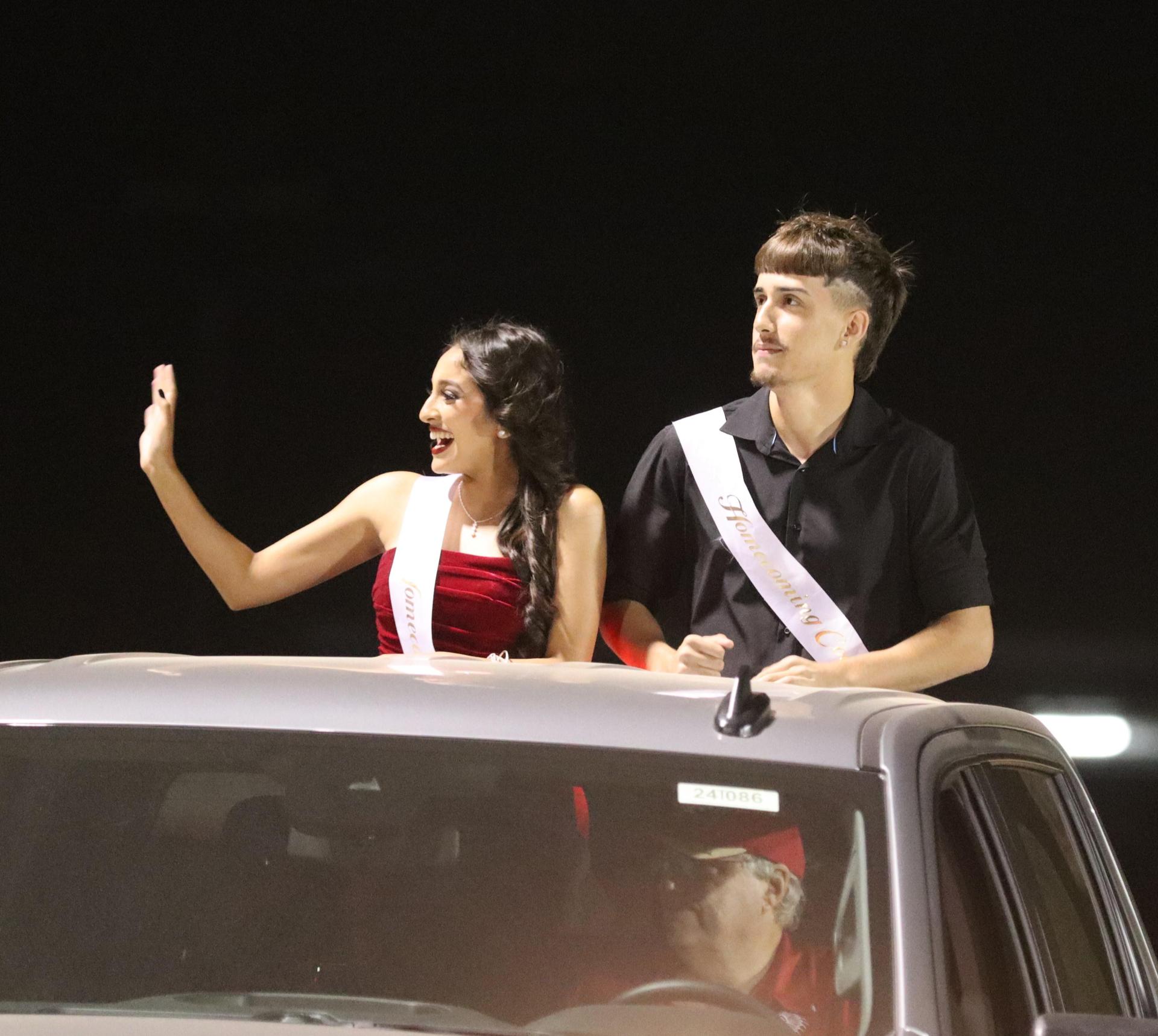 homecoming king and queen candidates entering the stadium in trucks