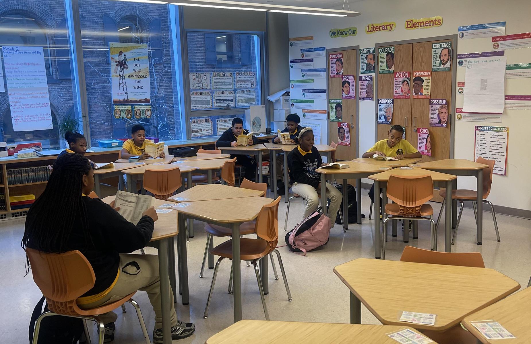 Students reading and working at desks in a classroom.