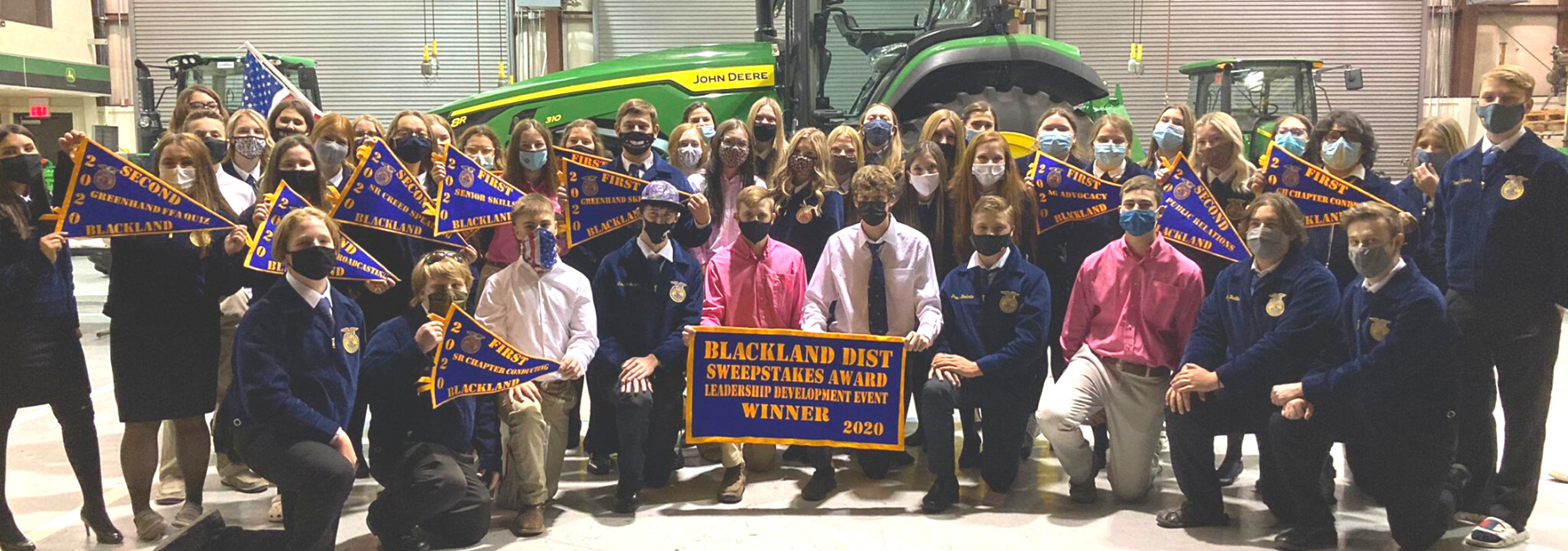 large group of students wearing FFA jackets holding award pennants