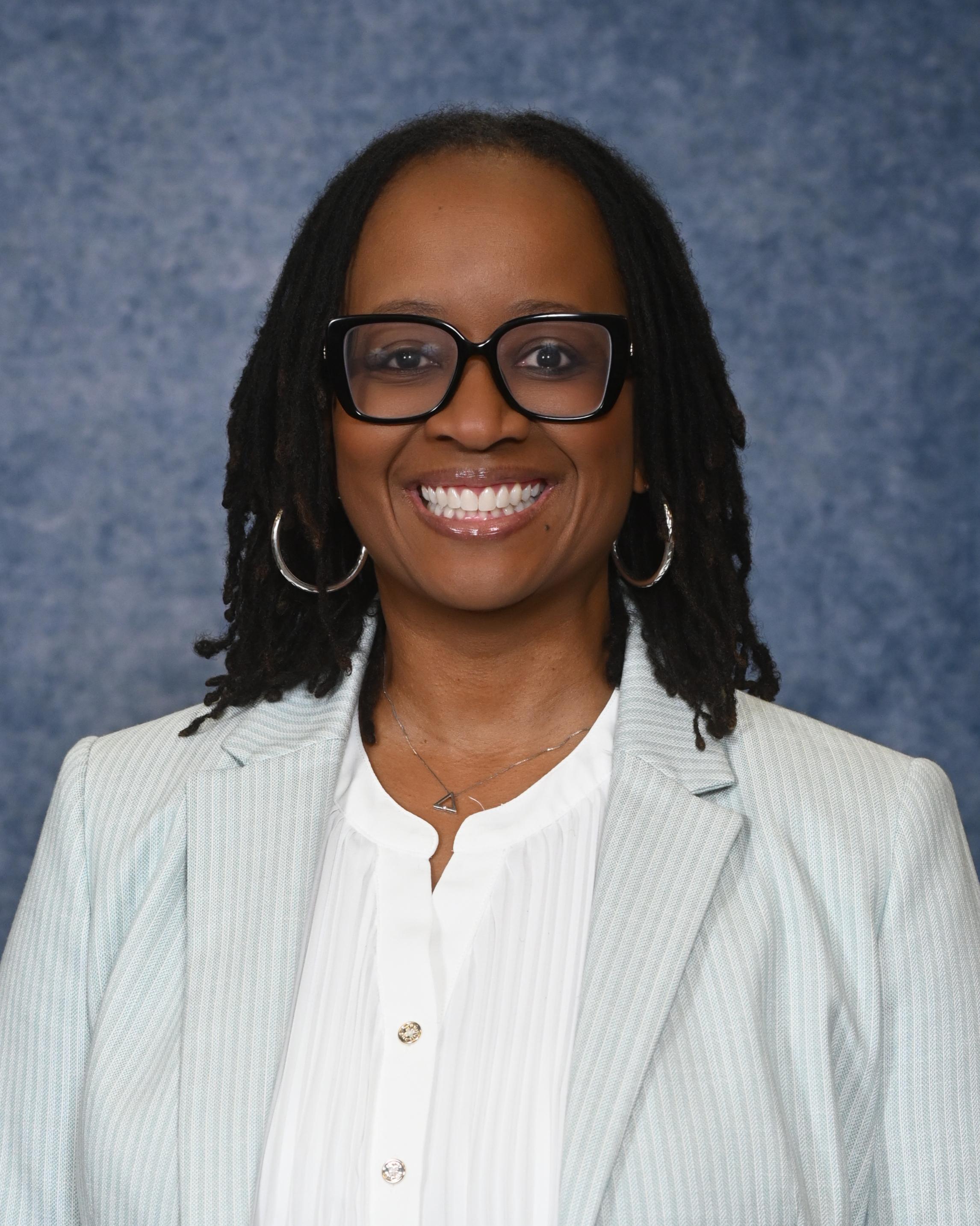 Image of Mrs. Jackson-Barnett from the chest up smiling in professional attire and glasses.