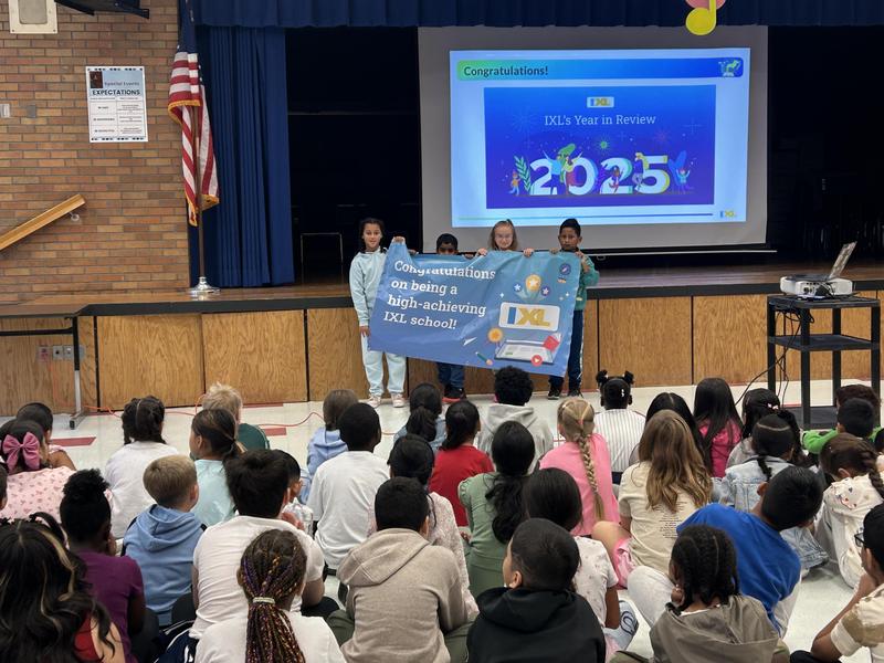 Image of 4 students holding a banner that says Congratulations on being a high achieving school! IXL