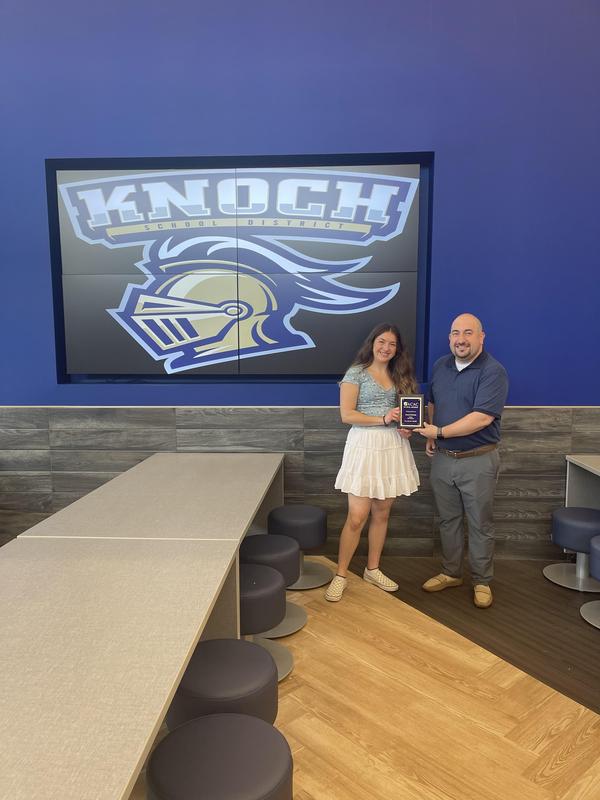 bald man handing plaque to high school girl in cafeteria