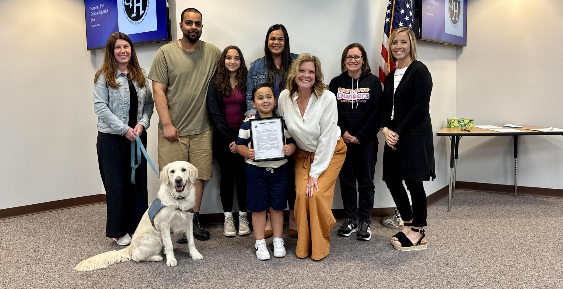 Group photo of the Mary Drew Early Learning Center Exemplary Student with his family and MDELC staff members taken during the May Board of Education meeting.