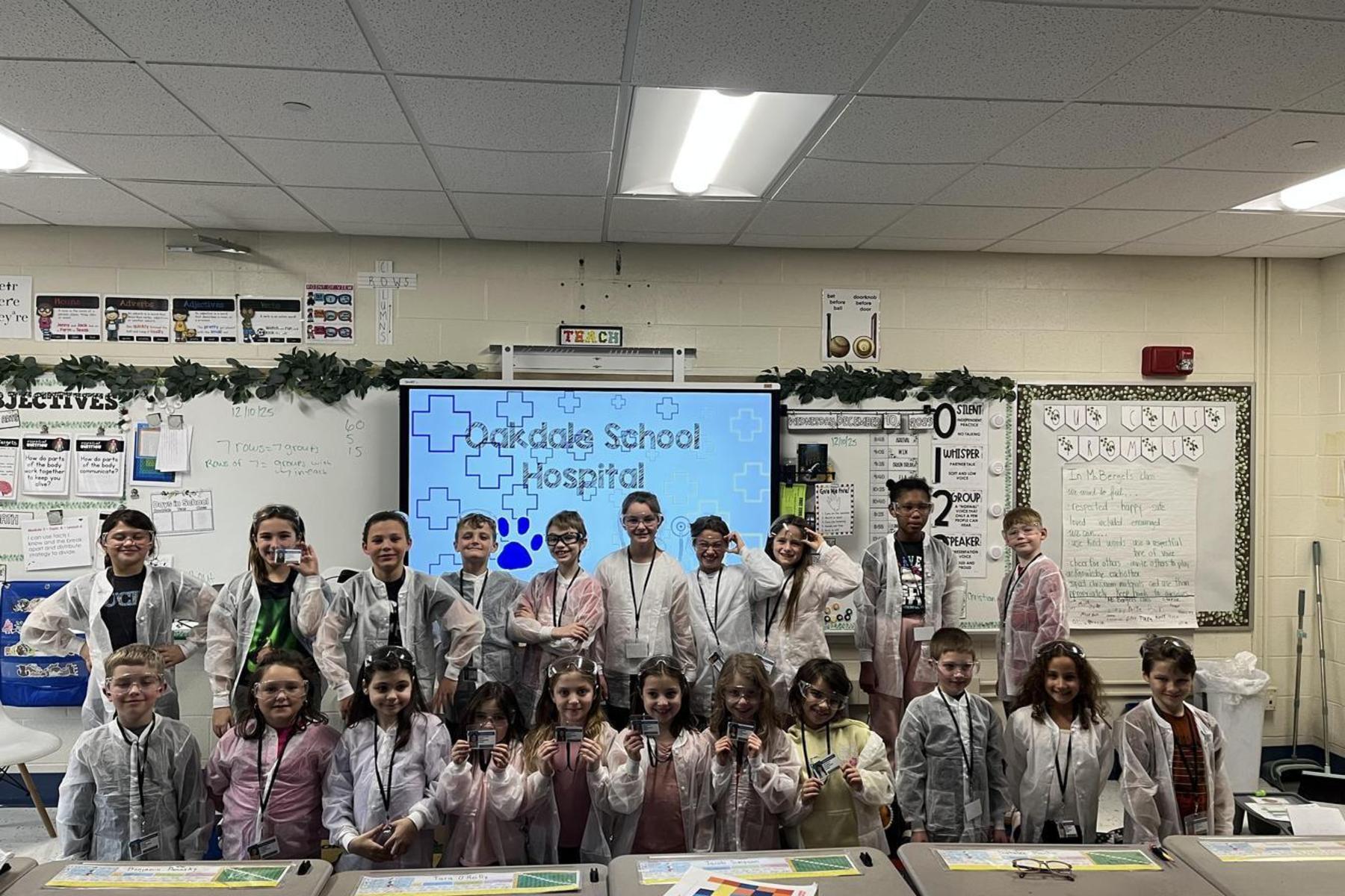 A group of children in lab coats in a classroom setting, showcasing a school hospital theme.