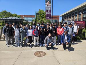 Group of students posing outdoors in front of a school building.