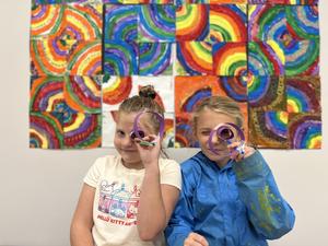 Students looking at camera through paper art