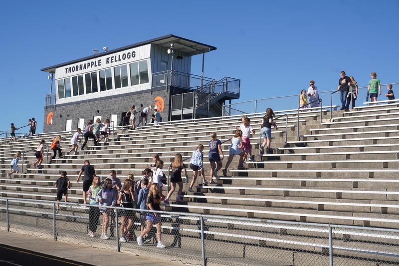 Teachers and students climb up and down the stairs in the stadium.