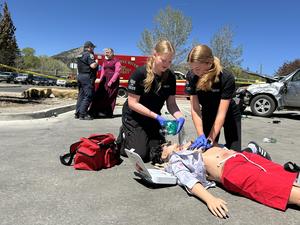 High school health science students perform CPR and intubation on a dummy at a mock crash site.