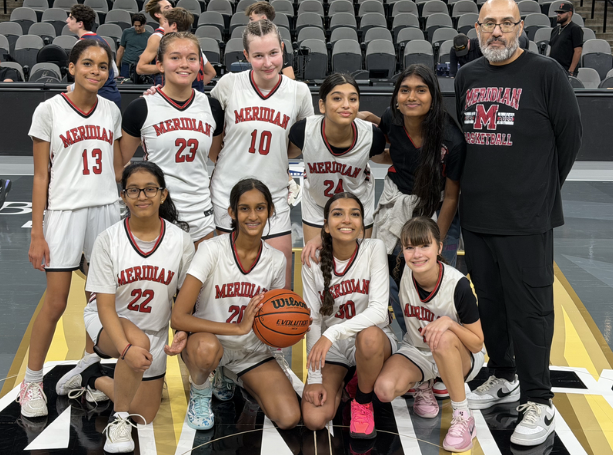 Girls varsity stands in a gym with their coach