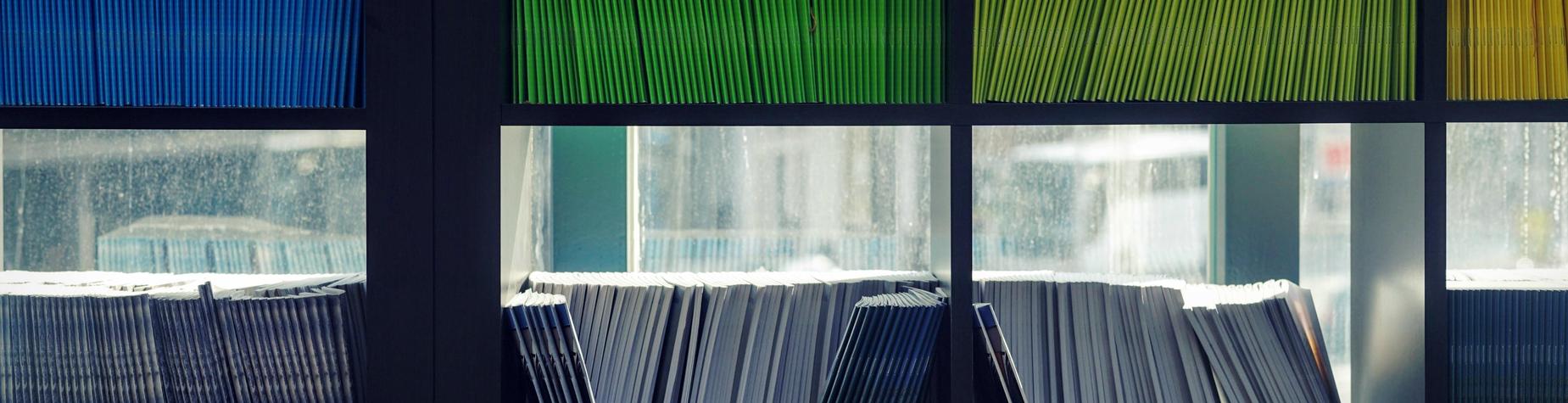 A shelf with colorful files organized by color, showcasing green, blue, and white folders.