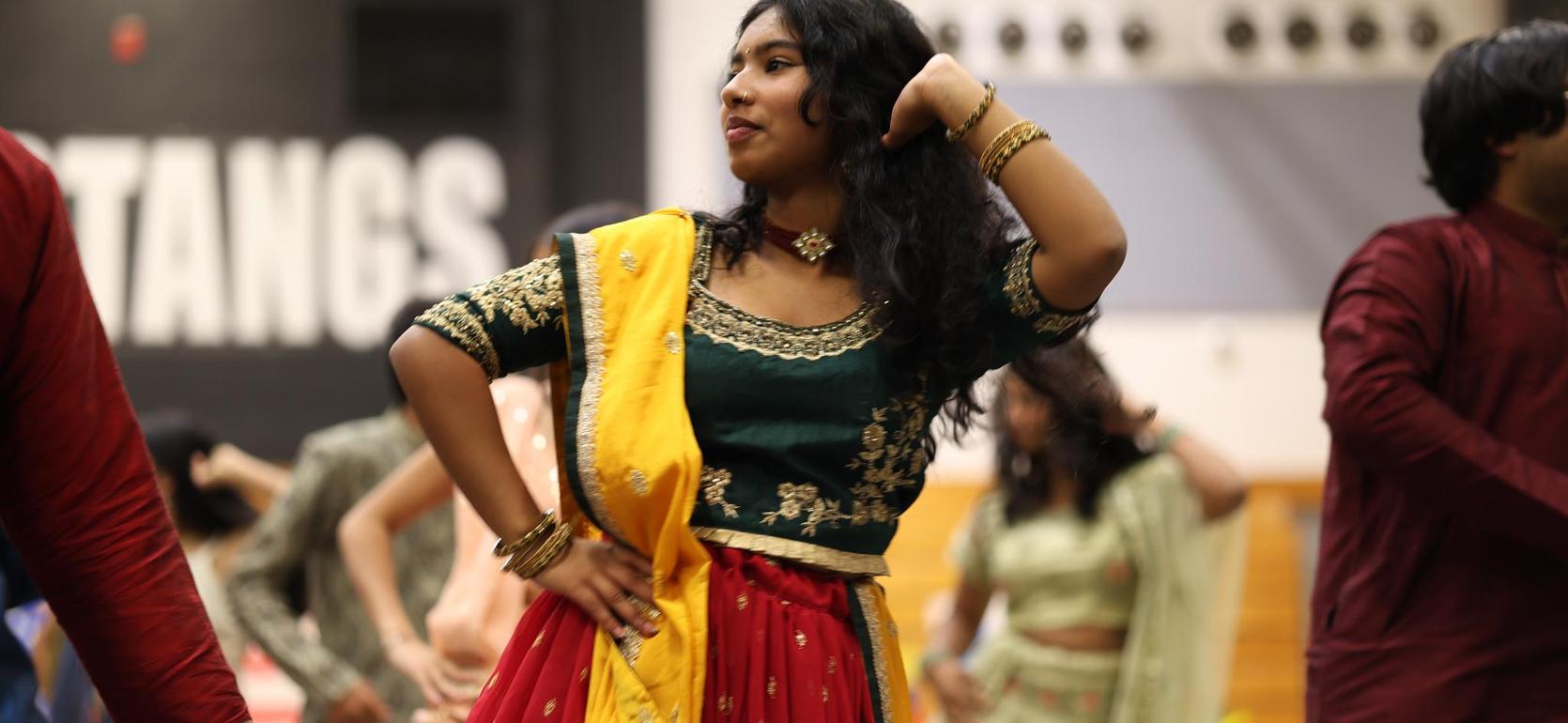 Woman in traditional attire dancing joyfully at a cultural event.