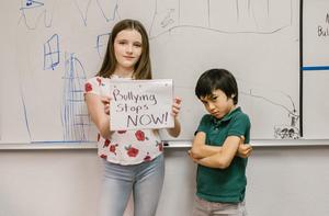 2 students with "bullying stops now" sign