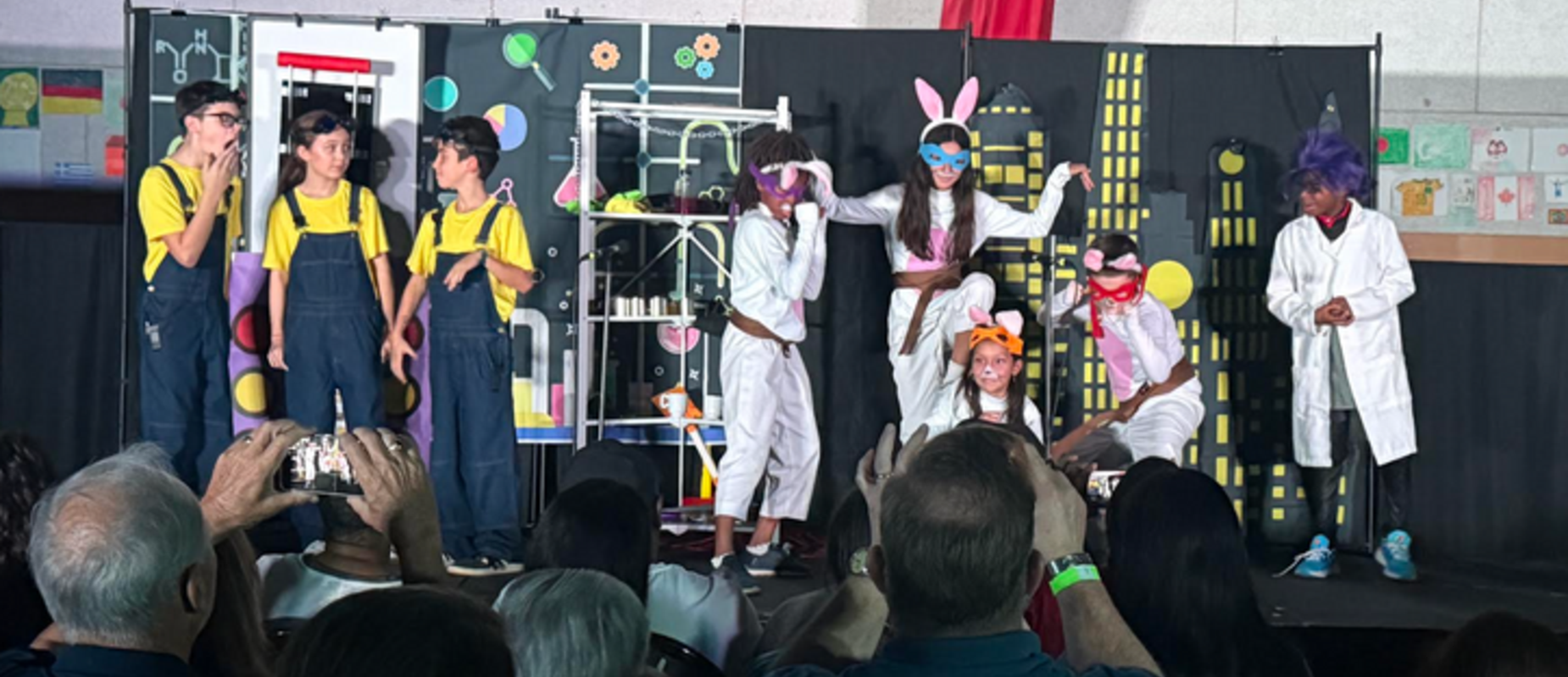 Students perform a play in the evening, dressed as minions and ninja bunnies