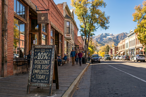 A sidewalk chalkboard sign reads "10% DISCOUNT FOR DSD EMPLOYEES TODAY" in a sunny, historic mountain town.