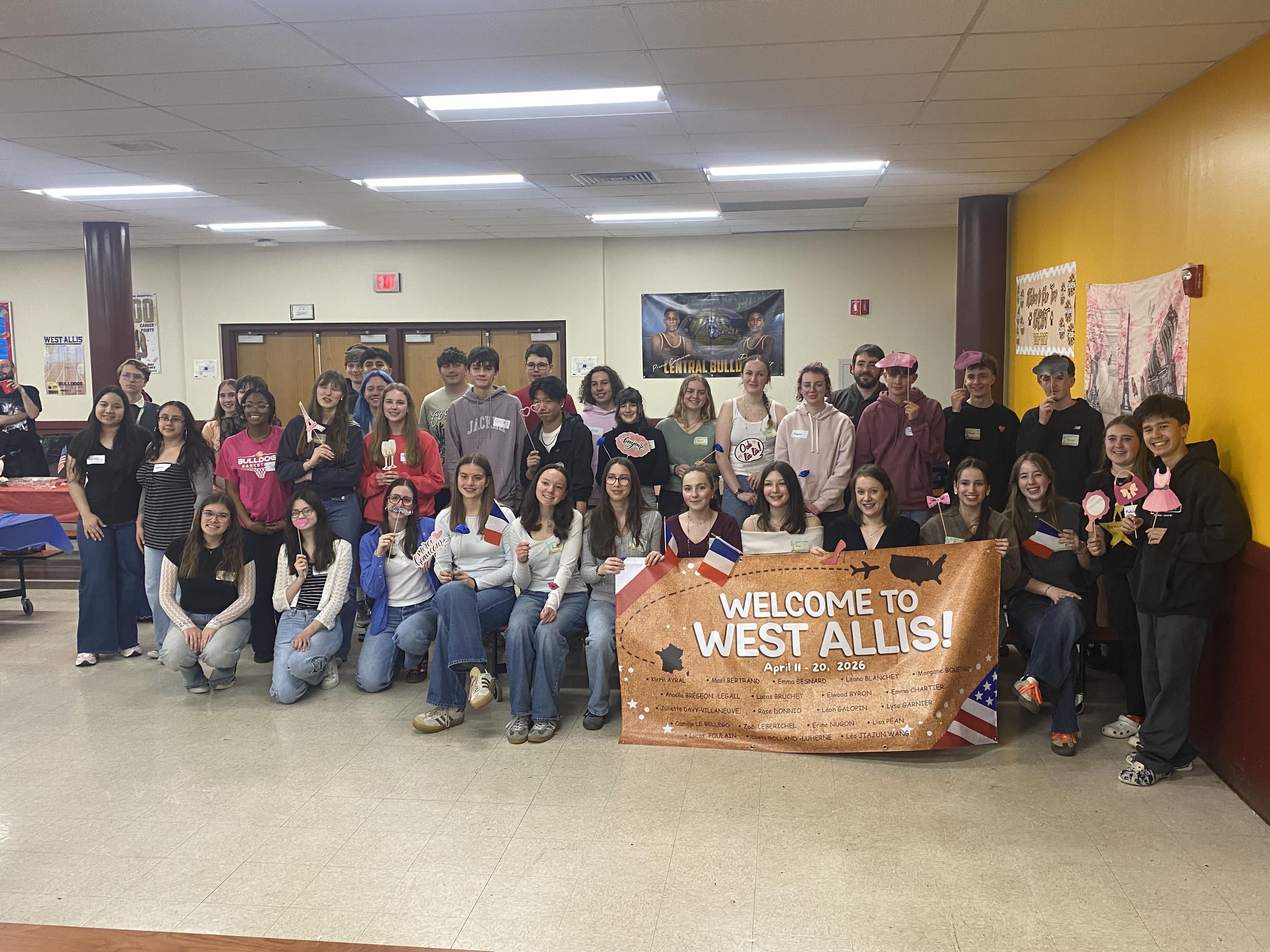 Group of people smiling with a welcome banner and decorations.