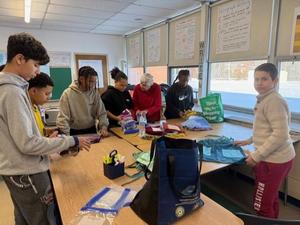 Students in a classroom organzing and folding fabric.