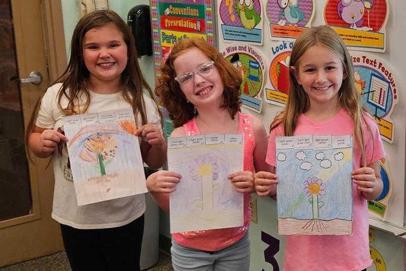 Samantha Younger, Iris Florio, and Brianna Keibler hold their drawings