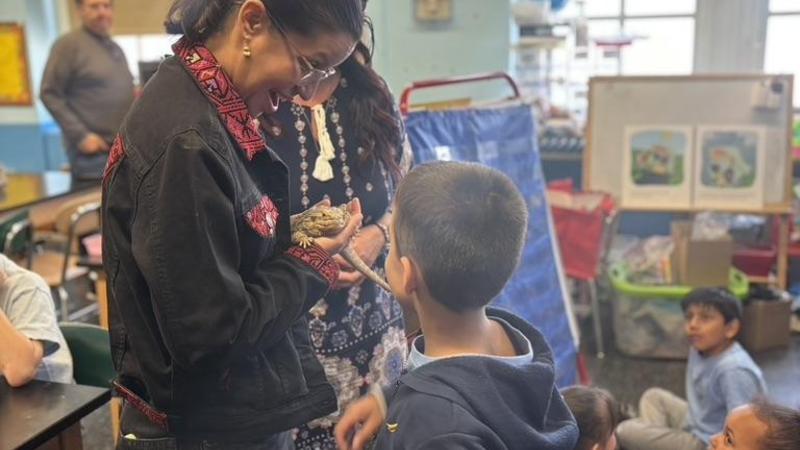 NYC Council Member holding a bearded dragon as students watch