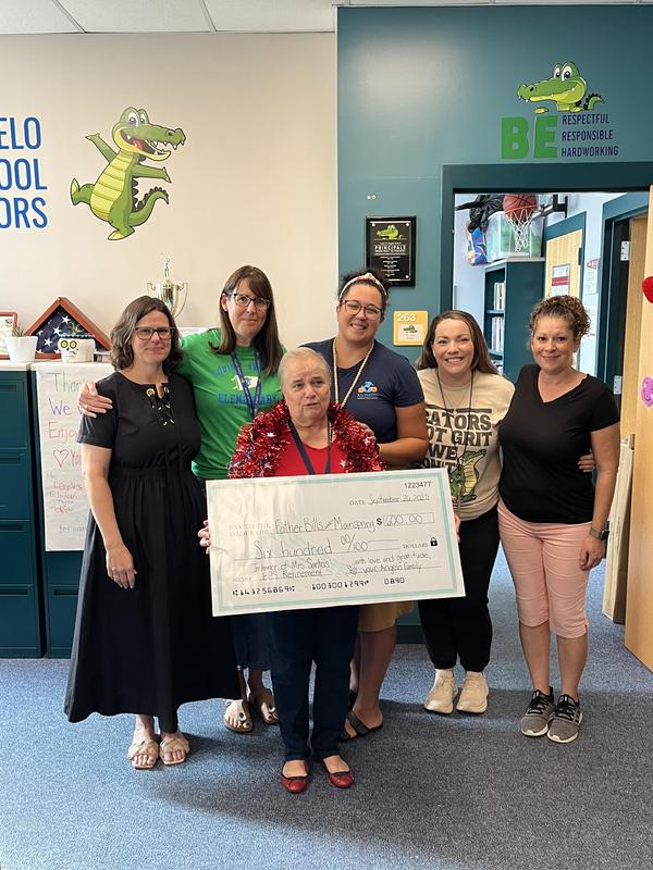 Manuela holds a large check along with colleagues