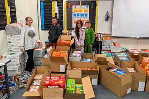 Student council student standing among 52 boxes of snack donations.
