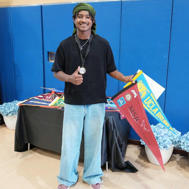Boy holding college pennants during MVHS Signing Day event