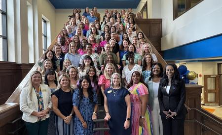 Group of diverse women gathered on a staircase, smiling for the camera.