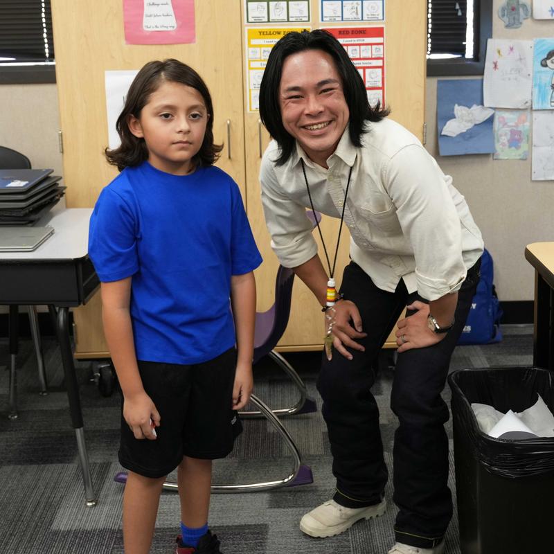 Student standing next to teacher in the classroom