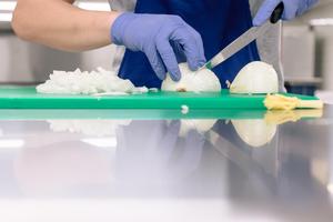 close up view of culinary student chopping an onion.