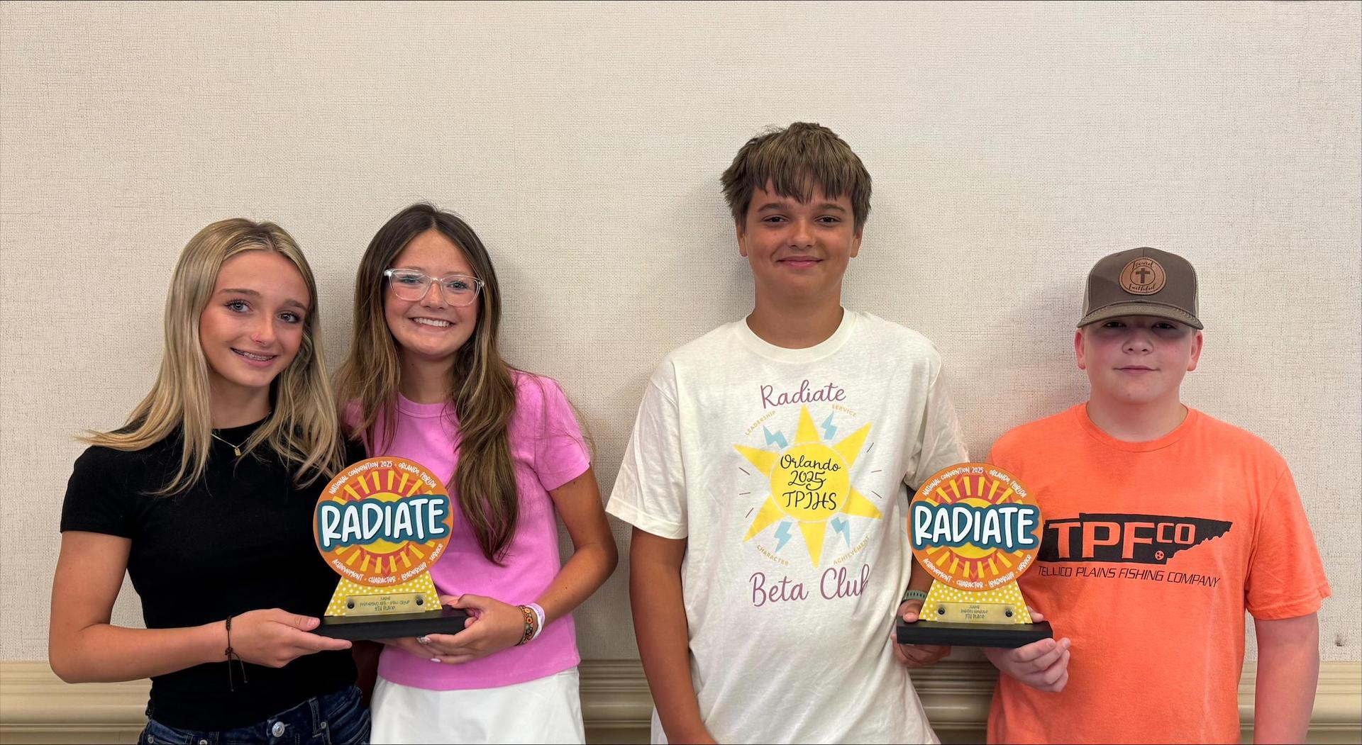 Four student holding two Radiate trophies. 