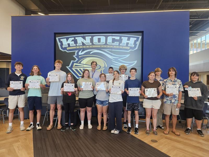 group of students standing in cafeteria holding certificates