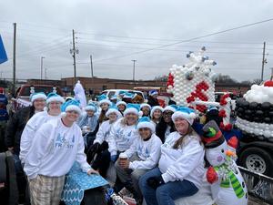 people in white shirts and blue santa hats sitting on a float in a parade