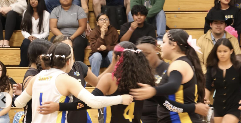 students share a team hug in the middle of the volleball court